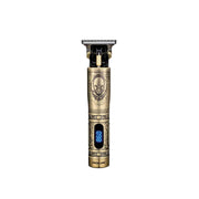 A gold-colored hair trimmer with an LCD display and a skull symbol on the metal body, resembling a pirate ship design.